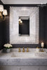 Luxurious bathroom with a rectangular decorative mirror with white selenite crystal sticks in a starburst pattern, Marble sink, and gold fixtures.